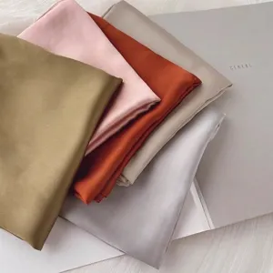 Détail de la texture douce des foulards en satin de soie de plusieurs couleurs
