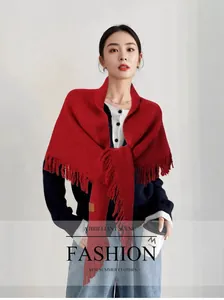 Elegante chal de punto rojo con borlas llevado sobre un jersey azul marino moderno