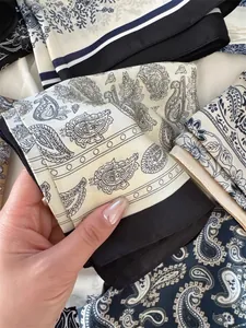Close-up of elegant paisley print silk scarf with black border detail for office wear