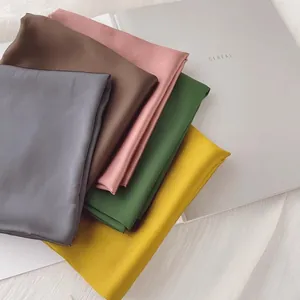 Vue détaillée de foulards carrés en satin de soie multicolores pliés de haute qualité