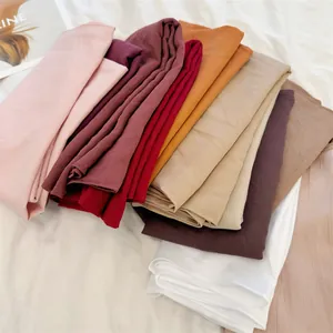Detail showing a stack of multiple colors of soft crinkle pleated 90cm square headscarves.
