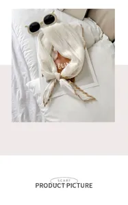 Close-up showing the elegant pleated texture and contrast border of the white silk scarf