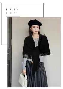 Modelo luciendo un chal triangular de punto negro con flecos para la moda de invierno.