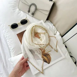 Macro view of elegant off-white pleated scarf with brown contrast border on fashion magazine
