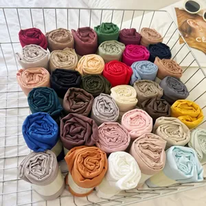 Large variety of pleated solid color cotton-blend hijabs rolled in a metal basket