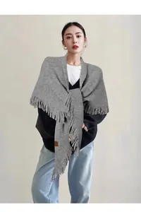 Primer plano de chal triangular de punto gris con elegantes detalles de flecos