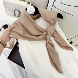 Detailed texture view of khaki crinkled cotton feel square scarf styled on a white dress.
