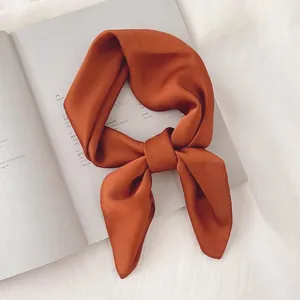 Gros plan d'un foulard en satin orange noué sur un magazine