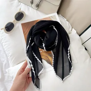 Detailed macro view of lightweight black pleated scarf with white contrast wavy border