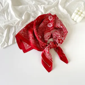 Red paisley silk scarf bandana tied in a knot on a white minimalist aesthetic background