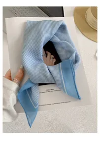 Close-up of a light blue and white gingham checkered square bandana scarf with solid blue borders
