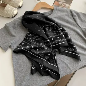Close-up of elegant black paisley silk scarf draped over a grey t-shirt fashionably