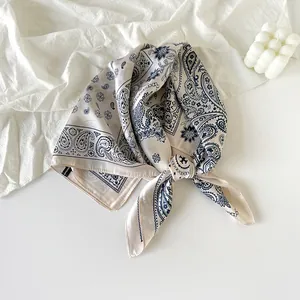 Detailed view of a navy blue paisley pattern silk scarf elegantly knotted on white fabric