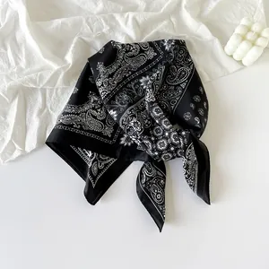 Detail shot of navy paisley silk scarf on white fabric with decorative candle