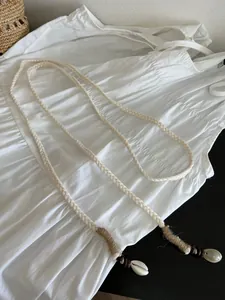 Detail van de Boheemse geweven katoenen riem met schelp- en kraaldetails.