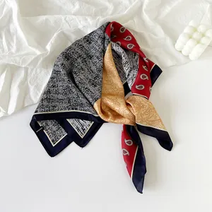Close-up of navy blue paisley and gold floral patterned silk neckerchief scarf