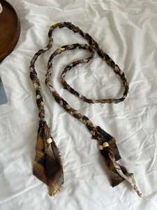 Boheemse gevlochten riem detail met geruite stofstrips en decoratieve houten kralen