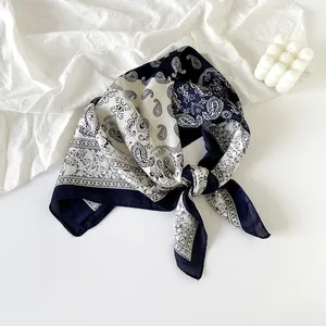 Elegant navy blue silk scarf with a white paisley pattern displayed on white fabric