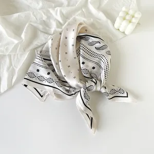Elegant cream silk-feel scarf featuring a black paisley pattern and knotted detail