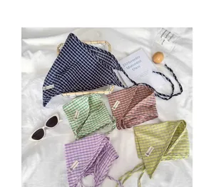 Dettaglio di vari foulard a triangolo a quadretti colorati su un panno bianco