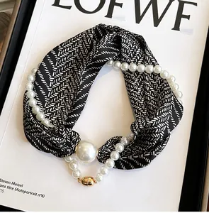 Vue détaillée d'un foulard en soie noir et blanc avec collier de perles et fermoir magnétique