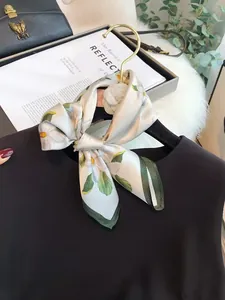 Elegant floral print silk scarf tied in a bow around the neck of a black garment