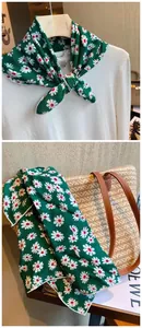 Detail of green floral cotton square scarf with daisy pattern on straw tote bag.