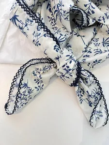 Close-up detail of a 100% cotton floral print neckerchief with navy blue lace trim.