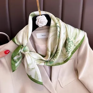 Elegant green and white floral silk square scarf styled on a beige blazer jacket