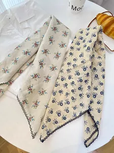 Detailed view of two 100% cotton floral print square scarves with scalloped crochet edges