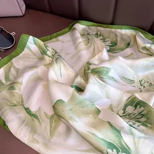 Close-up of silk square scarf featuring elegant green and white floral print