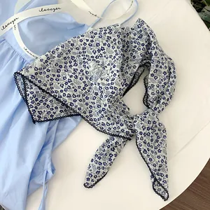 Detailed view of blue floral print on white cotton square scarf with scalloped edge