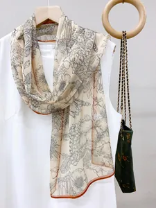 Detail of elegant floral print long scarf draped on a white dress for sun protection