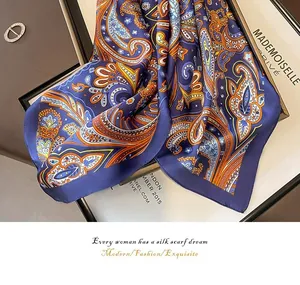 Detailed view of luxury paisley pattern on blue silk square scarf with satin finish.