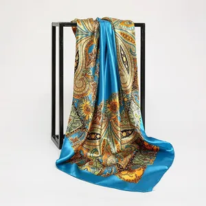 Elegant satin square scarf with vibrant blue paisley print draped on a minimalist frame