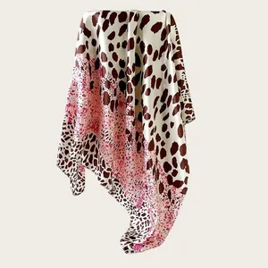 Detailed shot of a satin square scarf with vibrant leopard print pattern in pink and brown