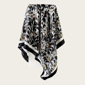 Detailed view of satin square scarf with abstract black and gold brushstroke pattern