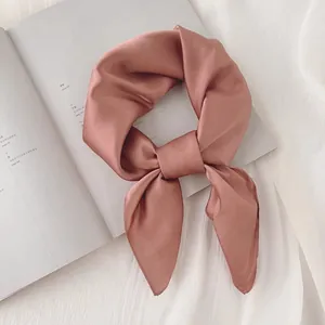 Détail d'un foulard en satin de soie vieux rose noué sur un magazine de mode