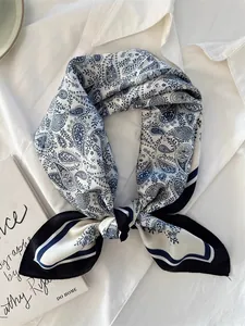 Detailed view of blue paisley silk scarf tied neatly on a white shirt background