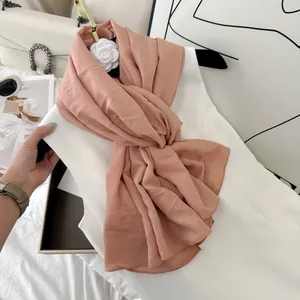 Elegant pleated pink scarf styled on a white dress with luxury fashion accessories