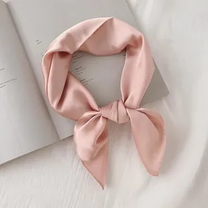 Vue détaillée d'un foulard en satin rose noué avec élégance sur un livre ouvert