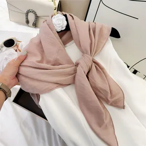 Detailed view of a soft dusty rose cotton-feel square scarf with fine pleats on a white dress