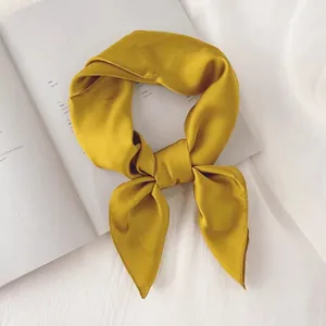 Carré de soie jaune élégant noué en boucle sur un magazine de mode chic. Style.