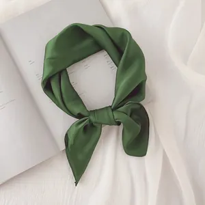 Gros plan détaillé d'un foulard en soie vert foncé noué avec élégance pour le cou
