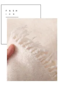 Primer plano de flecos suaves color crema en un chal triangular de invierno para mujer.