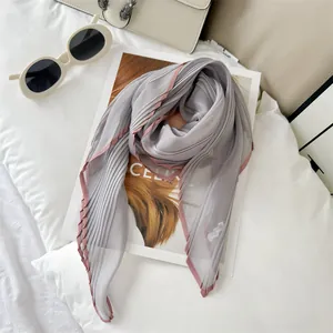 Close-up detail of lightweight pleated scarf with elegant pink contrast edging
