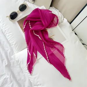 Close-up of magenta pleated sheer scarf with white contrast border on white bedding