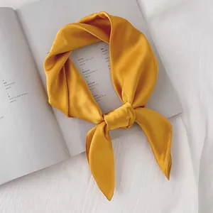 Gros plan détaillé d'un foulard en soie jaune moutarde uni noué de manière élégante