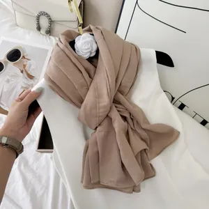 Detailed view of the soft pleated texture and fine stitching on a beige cotton blend scarf