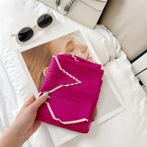 Detailed view of a lightweight pleated fuchsia silk scarf featuring elegant contrast piping